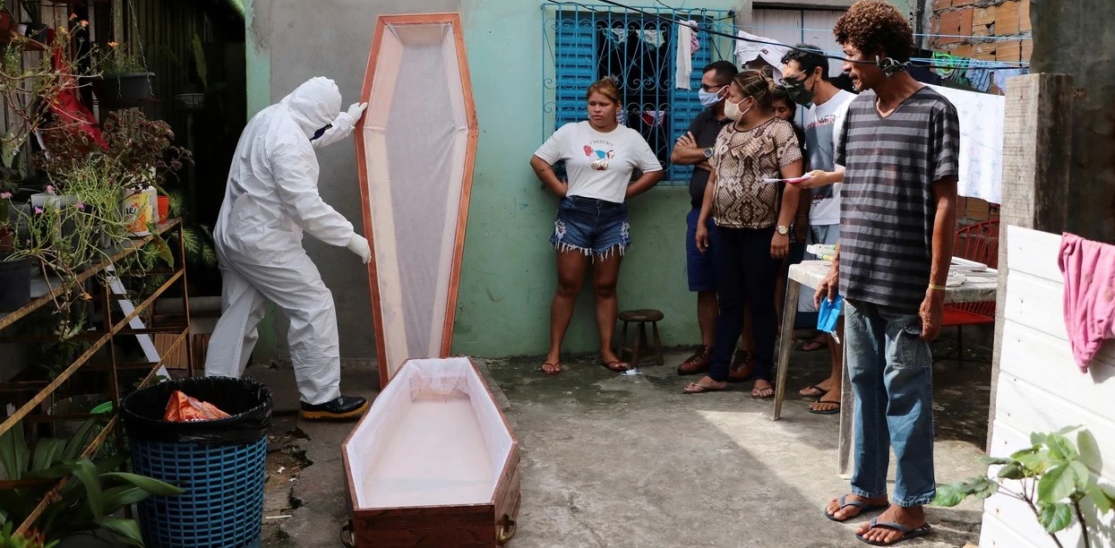 Personal de una funeraria usa traje de protección mientras prepara el ataúd para una víctima de coronavirus en Manaos, Brasil. / AP